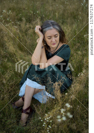 woman in whimsical aesthetic style dress in field in summer at sunset 117637174