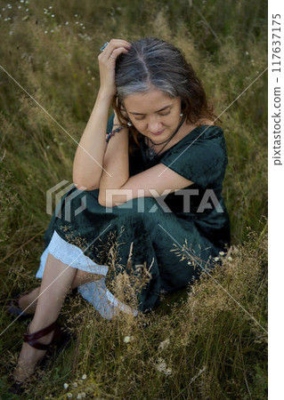 woman in whimsical aesthetic style dress in field in summer at sunset woman in whimsical aesthetic style dress in field in summer at sunset 117637175