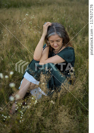 woman in whimsical aesthetic style dress in field in summer at sunset woman in whimsical aesthetic style dress in field in summer at sunset 117637176