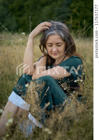 woman in whimsical aesthetic style dress in field in summer at sunset woman in whimsical aesthetic style dress in field in summer at sunset 117637177