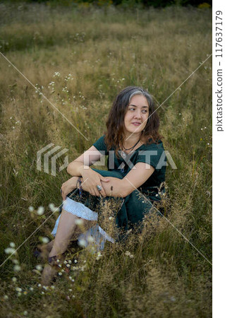 woman in whimsical aesthetic style dress in field in summer at sunset woman in whimsical aesthetic style dress in field in summer at sunset 117637179
