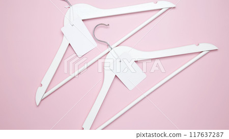 Creative flat lay hangers with white paper label. Clothing tag, label blank mockup template. Sale discount store promo shopping concept. Top view. Copy space 117637287
