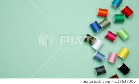 Multicolored sewing threads on green background. Top view, copy space Multicolored sewing threads on green background. Top view, copy space 117637306