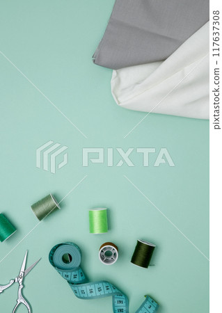 Composition with various threads and sewing accessories on green background. Top view, copy space Composition with various threads and sewing accessories on green background. Top view, copy space 117637308