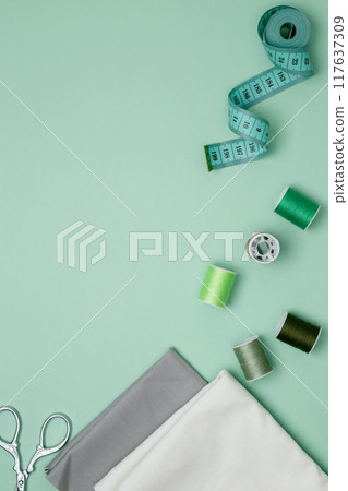 Composition with various threads and sewing accessories on green background. Top view, copy space 117637309