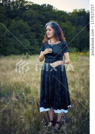 woman in whimsical aesthetic style dress in field in summer at sunset 117637357