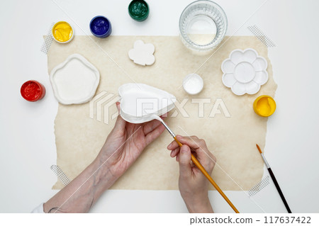 A woman paints clay products. Hobby clay modeling 117637422