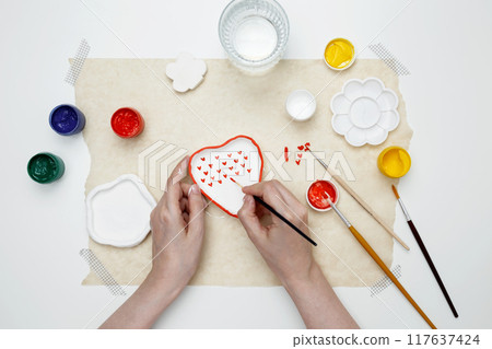 A woman paints clay products. Hobby clay modeling A woman paints clay products. Hobby clay modeling 117637424