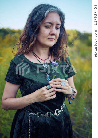 woman in whimsical aesthetic style dress in field in summer at sunset 117637453