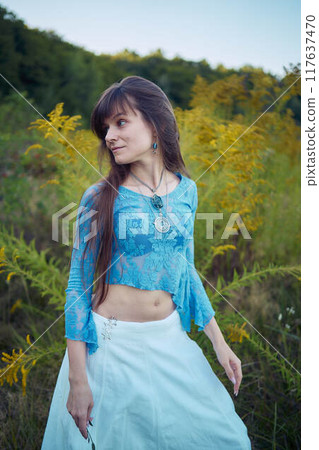 woman in whimsical aesthetic style dress in field in summer at sunset 117637470