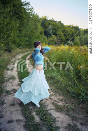 woman in whimsical aesthetic style dress in field in summer at sunset woman in whimsical aesthetic style dress in field in summer at sunset 117637499