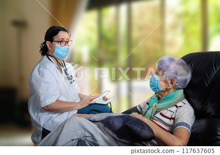 Masked Healthcare Worker Evaluates Senior Woman's Health at Her Home, Offering Personalized Medical Attention. 117637605