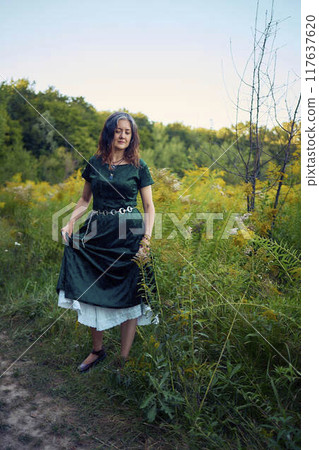 woman in whimsical aesthetic style dress in field in summer at sunset woman in whimsical aesthetic style dress in field in summer at sunset 117637620