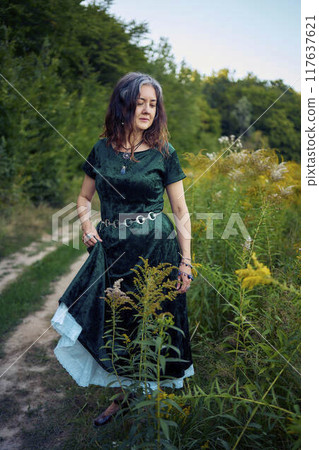 woman in whimsical aesthetic style dress in field in summer at sunset 117637621