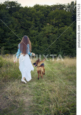 a woman in a Whimsical Aesthetic style dress with a German shepherd in a field 117637628