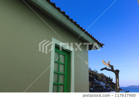 A simple green door on a rustic house against a clear blue sky by the seaside A simple green door on a rustic house against a clear blue sky by the seaside 117637980