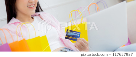 Young asian woman sitting on sofa using laptop computer shopping online with credit card. Young asian woman sitting on sofa using laptop computer shopping online with credit card. 117637987