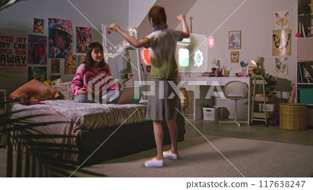 Teenager girl chats with virtual reality hologram sitting on bed Teenager girl chats with virtual reality hologram sitting on bed 117638247