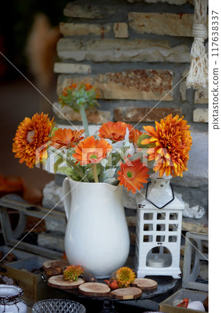 Large orange flowers in a white jug. Decorating cozy rooms 117638337