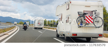 Scenic view group modern white family rv camper van vehicle drive Europe highway road alpine mountain cloud summer day overcast cloudy sky. Rving lifestyle travel community adventure  trip journey 117638570