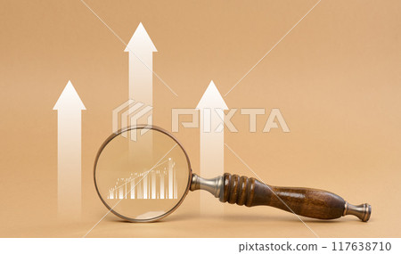 Magnifying glass and graph on brown background, business indicators growth 117638710