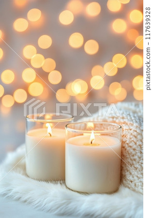 Softly glowing candles on a cozy blanket with warm bokeh lights in the evening 117639328