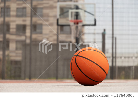 Basketball orange ball lying on court floor, outdoor public park at city. Basketball at courtyard. Sports gear without people. Template, sport background. Copy space. Close up. 117640003