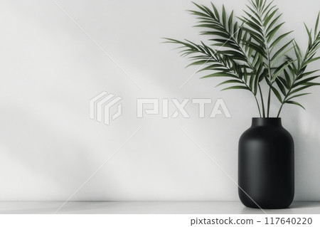 Black vase with green palm leaves on a minimalistic white background Black vase with green palm leaves on a minimalistic white background 117640220