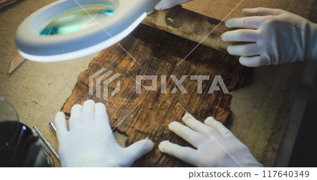 Close up of two archaeologists opening ancient Egyptian papyrus Close up of two archaeologists opening ancient Egyptian papyrus 117640349