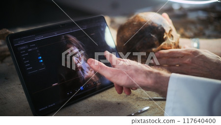 Two scientists examine fossil skull, discuss 3D model displayed on tablet screen 117640400