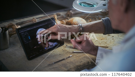 Archaeologists study 3D model of ancient human head displayed on tablet Archaeologists study 3D model of ancient human head displayed on tablet 117640402