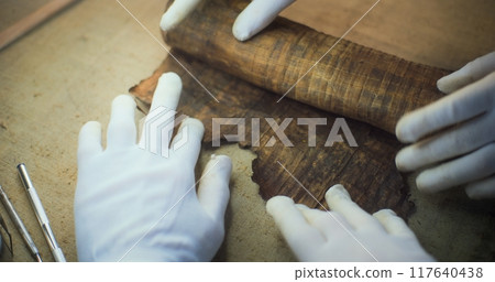 Scientists open ancient Egyptian papyrus on the table in archaeological lab 117640438