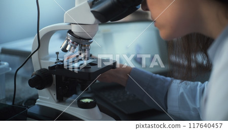 Close up of young scientist using microscope, analyzing sample Close up of young scientist using microscope, analyzing sample 117640457