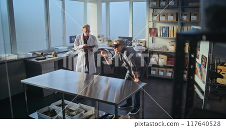 Two archaeologists conduct scientific research using tablet computer and AR headset 117640528
