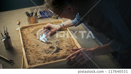 Mature archaeologist takes measurements of dinosaur skeleton Mature archaeologist takes measurements of dinosaur skeleton 117640531