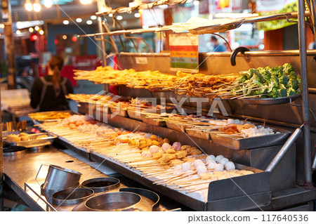 Small local street Asian shops with an assortment of fresh skewers with fish, meat and vegetables for cooking. Small local street Asian shops with an assortment of fresh skewers with fish, meat and vegetables for cooking. 117640536