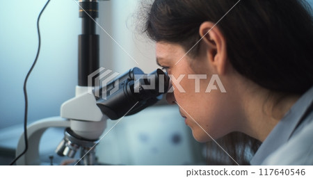 Close up of young scientist using microscope, analyzing sample Close up of young scientist using microscope, analyzing sample 117640546