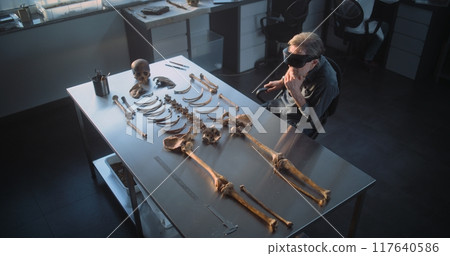 Archaeologist in VR headset does historical research with remains of ancient human 117640586