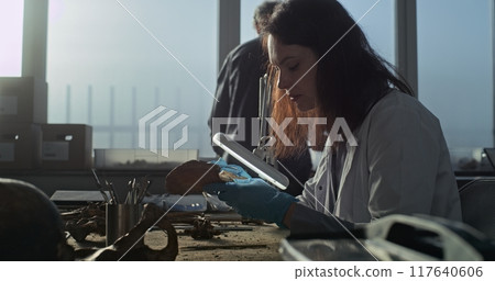 Young female scientist works with fossil remains of prehistoric human bones 117640606