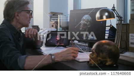 Scientist uses tablet and computer with 3D visualization of ancient extinct human head 117640608