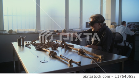 Mature archaeologist conducts historical research using virtual reality 117640652