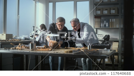 Senior paleoanthropologist takes photo of fossil remains with colleague 117640688