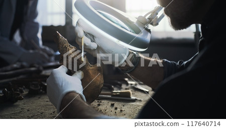 Mature archaeologist studies bones of ancient human and cleans with brush 117640714