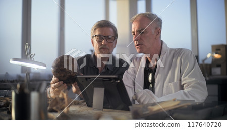 Two archaeologists examine fossil skull, use tablet computer 117640720