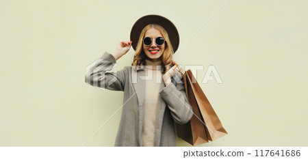 Autumn portrait of beautiful young woman with shopping bag, stylish girl in coat on brown background Autumn portrait of beautiful young woman with shopping bag, stylish girl in coat on brown background 117641686