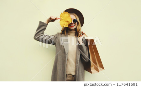 Autumn portrait of beautiful happy woman with shopping bag, stylish girl holding yellow maple leaves Autumn portrait of beautiful happy woman with shopping bag, stylish girl holding yellow maple leaves 117641691