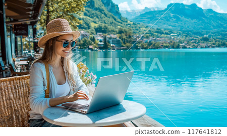 一位婦女在湖邊用筆記型電腦工作的寧靜風景，周圍環繞著大自然，在安靜的環境中遠端工作 117641812