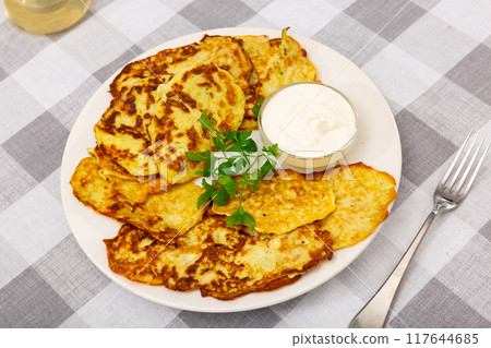 Zucchini pancakes served with sour cream Zucchini pancakes served with sour cream 117644685