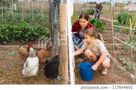Young woman with little girl feeding poultry 117644691