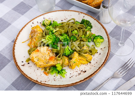 Authentic Italian fettuccine pasta dish with chicken breast and broccoli on table 117644699